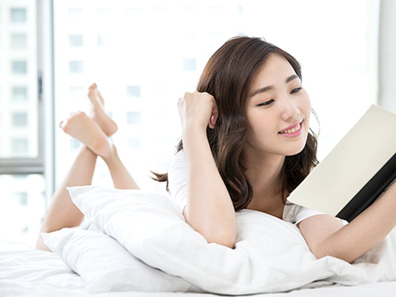 침대에 누워 책을 읽으며 쉬는 여성